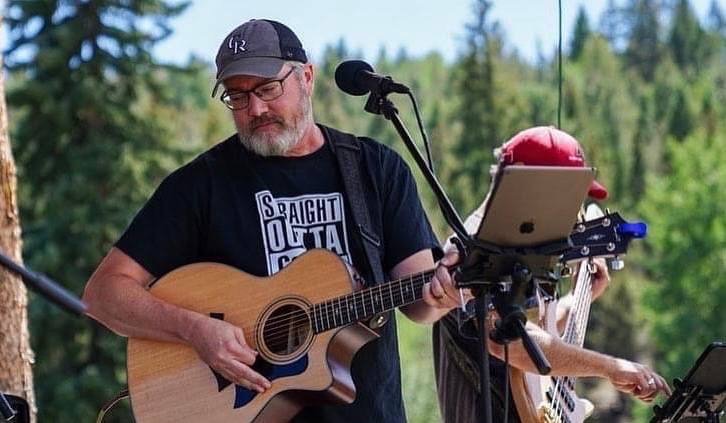 Lance playing acoustic guitar at an outdoor show